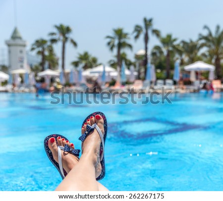 Woman wearing flip-flops laying on the sunbed near the pool