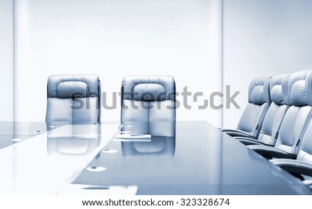 Conference room with wooden table and beige leather armchairs, blue toning