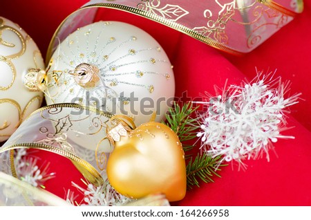 Chrismas decorations: two silver baubles, golg heart and ribbon ot red velvet background