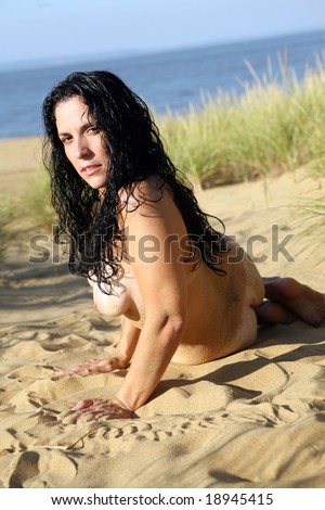 stock photo : Nude Girl, kneeling on Sandy beech by tall grass, looking at