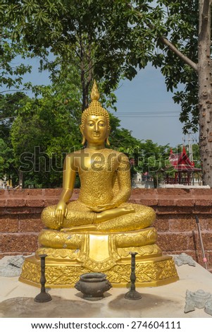 the gold buddha statue sitting with candlestick and incense burner under sunlight