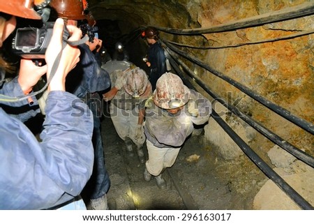Potosi, Bolivia - 24 November 2012: Tourists inside the Cerror Rico silver mine film miners transporting ore. Potosi is one of the highest cities in the world and nearby Cerro Rico has a long history
