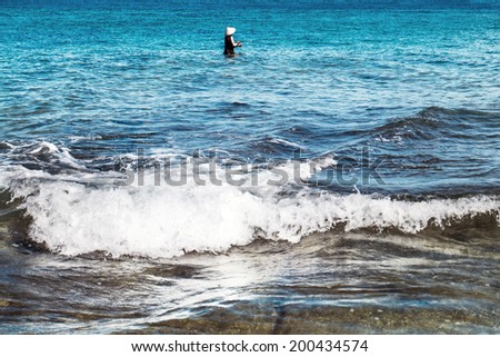 Local fisherman standing in the sea, holding a fishing rod to catch fish, Lombok Island, Lesser Sunda Islands, Indonesia, Asia