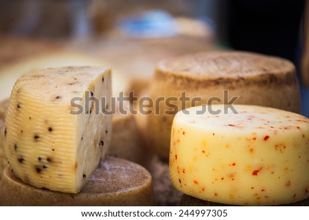 Wheels of cheese seasoned with herbs to sell on stall