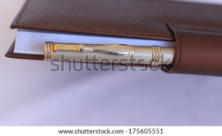 Brown note book and pen on white isolated