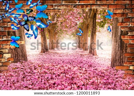 An alley with pink flowers can be seen through the brick wall