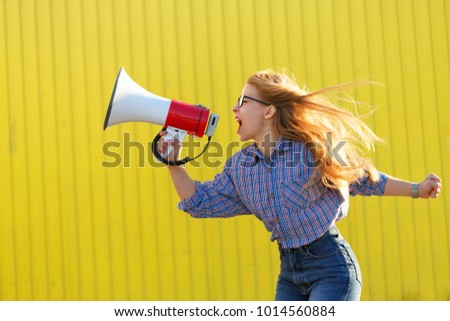 Young attractive girl activist in shirt yelling into loudspeaker. A single picket. Active life position. The struggle for women\'s rights