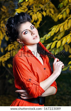 Young attractive girl in red shirt and with makeup close-up portrait in autumn park