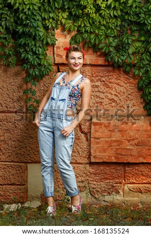 Beautiful pin-up girl in denim overalls and a T-shirt outdoors