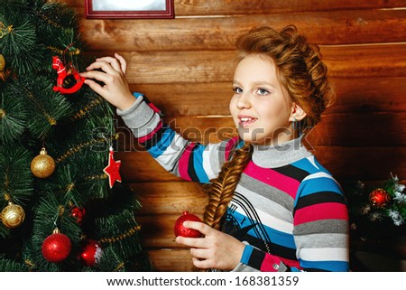 Little girl with plait Christmas tree decorates toys