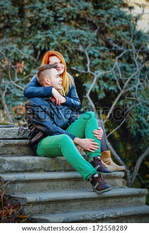 Attractive young couple sitting on the steps and hugging each other