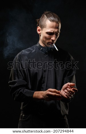 Portrait of smoking man with a cigarette in his hand on a dark background shot in studio