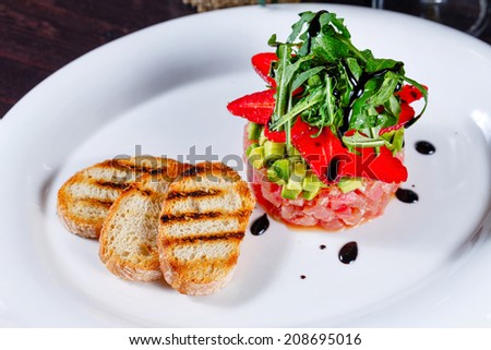 Tuna tartare with fruit strawberries and toasted toast shot close-up in a restaurant