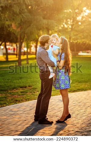 Happy family mother, father and daughter walk in autumn park. Daughter holding a lollipop