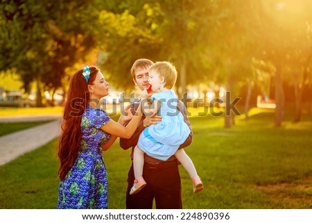 Happy family mother, father and daughter walk in autumn park. Daughter holding a lollipop