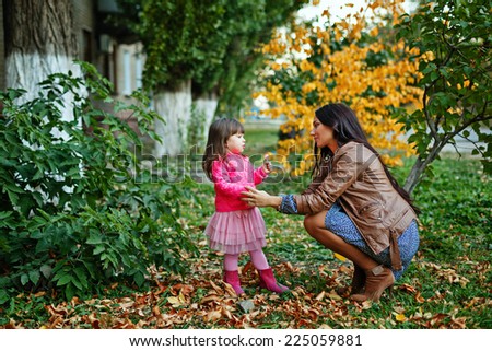 Young mother and daughter walking in the autumn park
