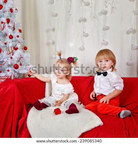 Little brother and sister sitting on the couch near Christmas tree