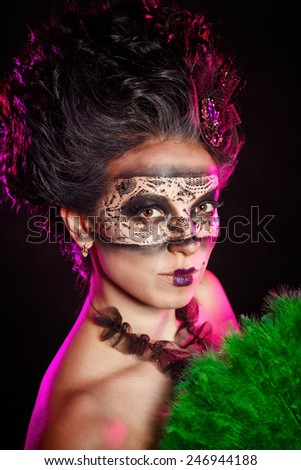 A mysterious young girl in masquerade mask holds in her hands a fan. Girl flirts.