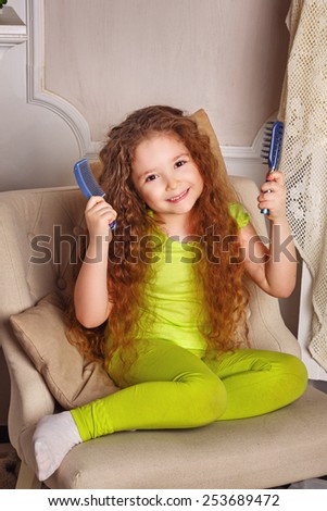 Portrait of a little girl with long curly hair brushing her hair