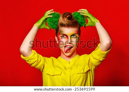 Cheerful girl with make-up broccoli demonstrates positive emotions. Concept of healthy food and organic products.