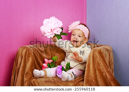 Little girl sitting in chair with a happy look on her face hold flowers shot in home interior