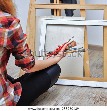 The artist holds in her hands a brush. Unrecognizable people