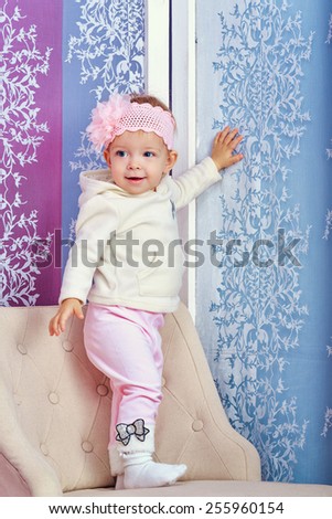 Little girl sitting in chair with a happy look on her face shot in home interior