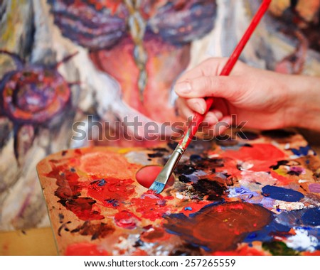 Artist brush mix color oil painting on palette is holding in his hand closeup