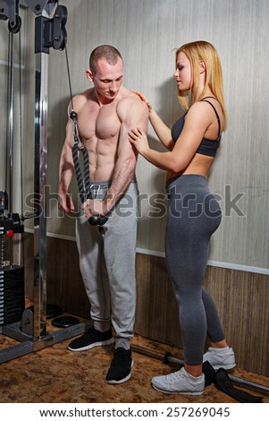 Coach with a client in the gym. Sports Man and athletic girl engaged in fitness in the gym.