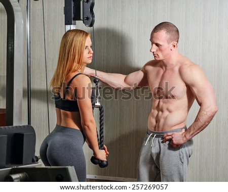 Coach with a client in the gym. Sports Man and athletic girl engaged in fitness in the gym.