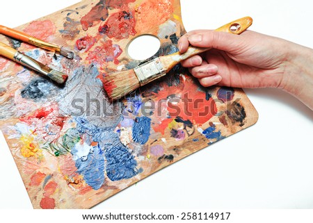 The artist paints a picture of a paint brush in his hand with a palette closeup