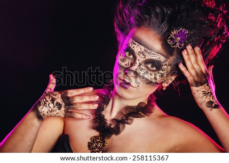 A mysterious young girl in a mask and with an unusual makeup close-up portrait
