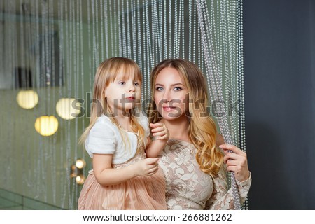 Young mother hugging her daughter tenderly. Mother holds daughter on hands. The concept of family happiness.
