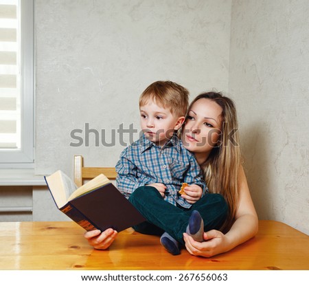 Mother and son reading a book. Mother holding a book hugging son. Happy family leisure.