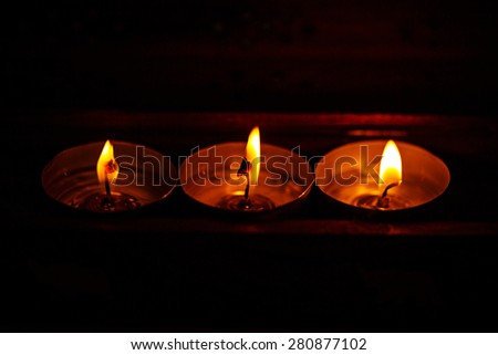 Three candles on a dark background in a warm light. The concept of home comfort.