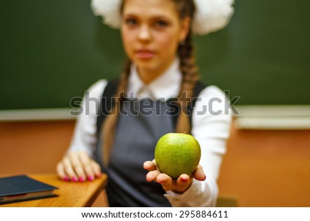 Excellent pupil holds a green apple on his hand. Focus on the apple. Back to school.