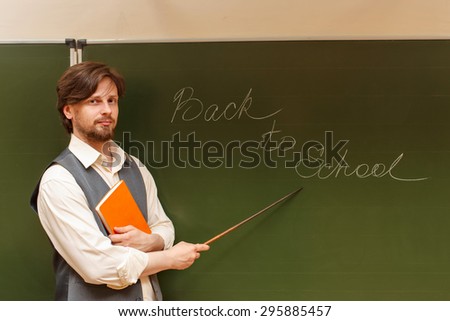 The teacher shows the inscription on the back to school. The inscription on the blackboard with chalk. The concept of modern education. Back in college.