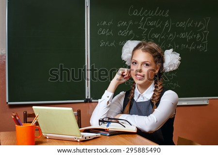 Excellent pupil sitting at a desk. On the table is a laptop. On the blackboard writing formulas geometry. Lesson calculus. The concept of modern education. Back to school.