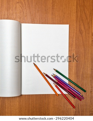 Colored pencils lie on a school notebook. Blank sheets of paper. Back to school.