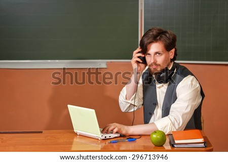 The teacher listens to music and talks in a video conference during a break between classes. Back to school.