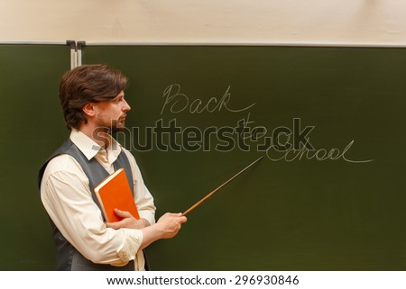 The teacher shows the inscription on the back to school. The inscription on the blackboard with chalk. The teacher is holding a notebook. The concept of modern education. Back in college.