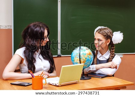 Education concept. Back to school. Teacher and pupil in geography class. On the table is a globe.