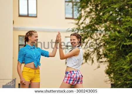 Best friends teenagers met at a summer park. Girls dressed in shorts and a shirt. Teens give five. The concept of true friendship. High-five