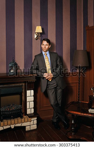 Successful businessman standing by the fireplace. Vintage background. Leadership concept.