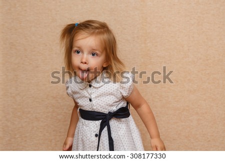 Little cute girl shows tongue. Positive emotions. The concept of carefree childhood.