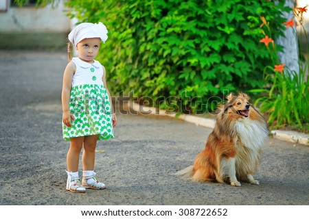 Little girl and dog sheltie walk in the park. The girl was offended.