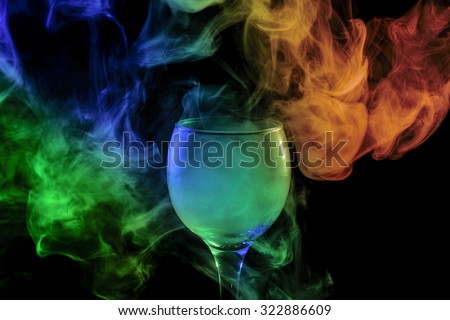 Abstract art. Hookah blue - green and orange smoke into the cocktail glass on a white background. Witch potion background for Halloween. Unusual bar drink. Drink in glass with the effect of dry ice.