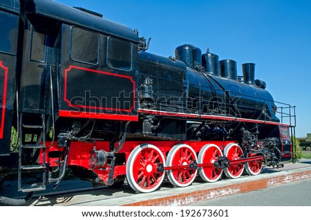 Old Russian (Soviet) steam locomotive on a pedestal on a background of blue sky