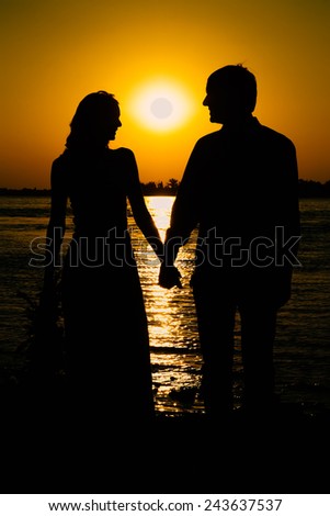 Young couple in love meet sunrise (sunset) on the banks of the river.