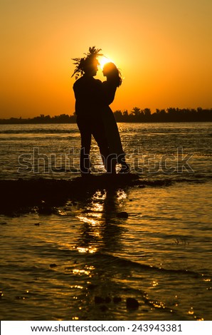 Young couple in love meet sunrise (sunset) on the banks of the river.